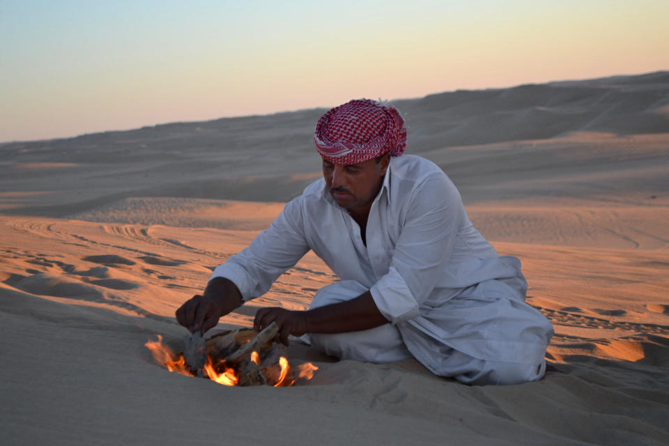 This September 2012 photo shows desert safari driver Ahmed Bakrin building a small bonfire to make mint tea before sunset during a trek through the Great Sand Sea outside the Egyptian oasis of Siwa, a Berber town of some 27,000 people roughly 450 miles (about 725 kilometers) southwest of Cairo. The palm tree-lined area is known for its quiet charm, ancient ruins, abundant natural springs, a vast salt lake and rolling sand dunes in the surrounding desert. (AP Photo/Kim Gamel)