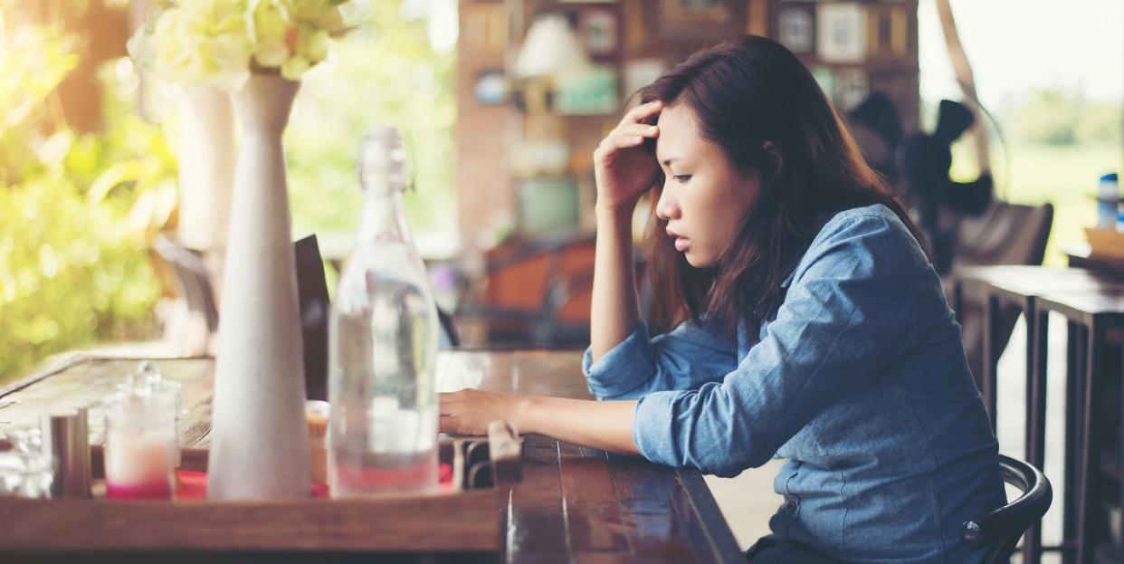 Side View Of Tensed Young Woman Sitting At Cafe