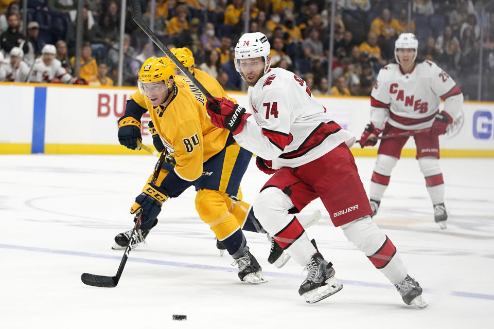 Nashville Predators left wing Tanner Jeannot (84) and Carolina Hurricanes defenseman Jaccob Slavin (74) chase the puck in the first period of an NHL hockey game Saturday, Oct. 16, 2021, in Nashville, Tenn. (AP Photo/Mark Humphrey)