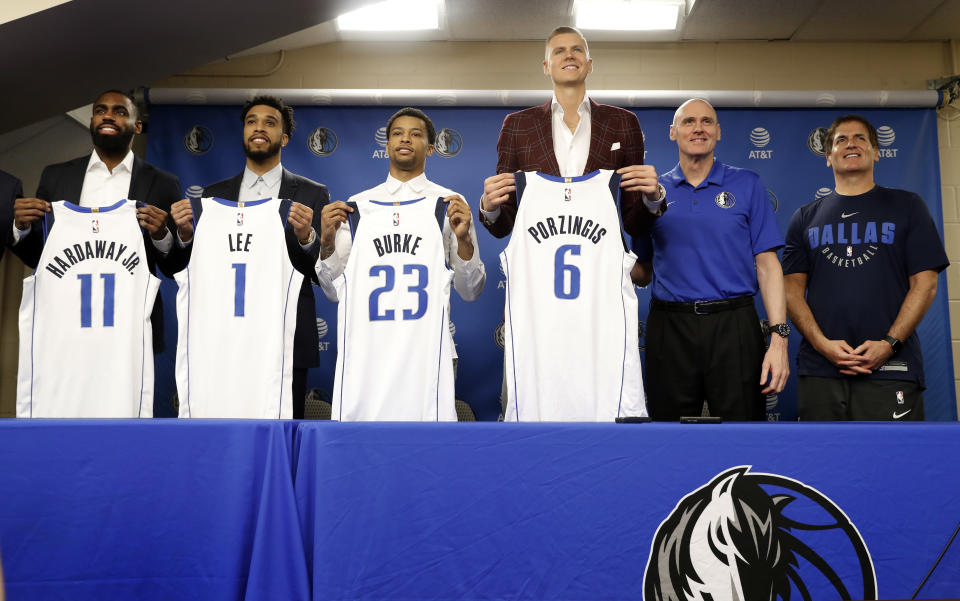 Dallas Mavericks' Tim Hardaway Jr. (11), Courtney Lee (1), Trey Burke (23) and Kristaps Porzingis (6) pose with their new jerseys along side head coach Rick Carlisle, second from right, and team owner Mark Curban, right, during a news conferences where the newly acquired players were introduced in Dallas, Monday, Feb. 4, 2019. (AP Photo/Tony Gutierrez)