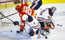 Edmonton Oilers' Cody Ceci (5) checks Calgary Flames forward Blake Coleman, left, who scores an apparent goal that was called off after review, while goalie Mike Smith loses track of the puck during the third period of Game 5 of an NHL hockey second-round playoff series Thursday, May 26, 2022, in Calgary, Alberta. (Jeff McIntosh/The Canadian Press via AP)