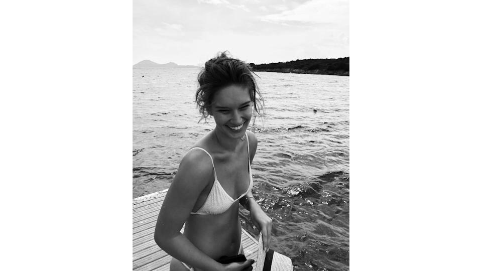 black and white photo of a woman in a bikini by the sea