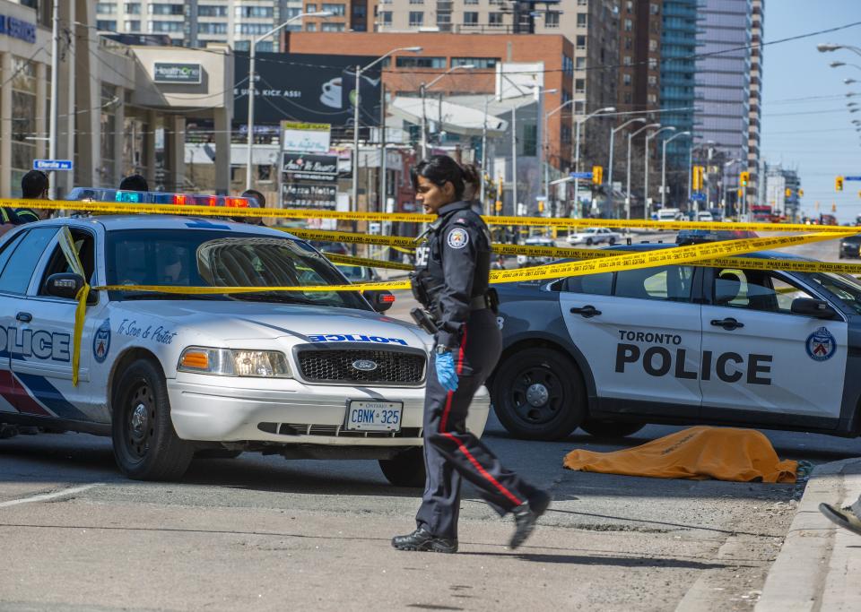 Vista de un cuerpo cubierto (d) después de que una camioneta alquilada recorriera la acera golpeando a los peatones hoy, lunes 23 de abril de 2018, en la calle Yonge en el norte de Toronto (Canadá). EFE/WARREN TODA