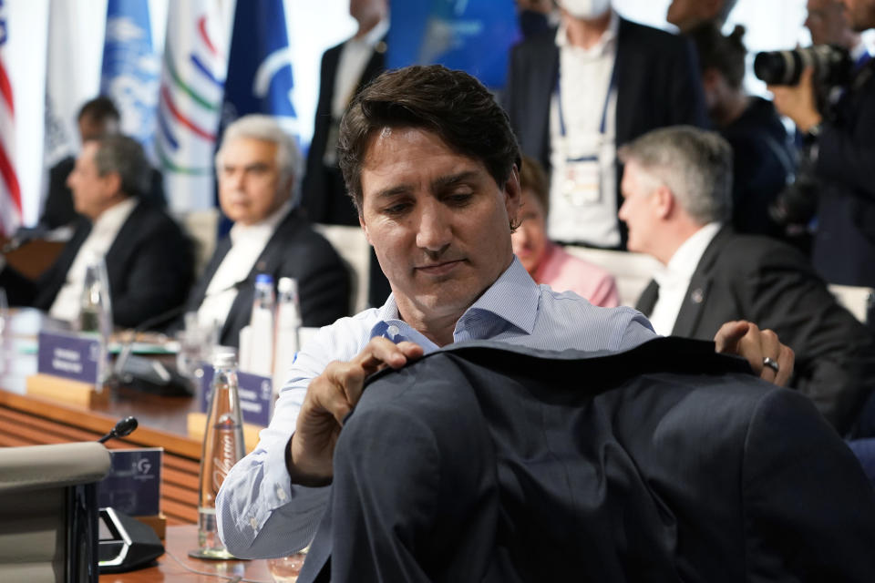 Canada's Prime Minister Justin Trudeau hangs his coat on the back of his chair as he waits for the start of a lunch with the Group of Seven leaders at the Schloss Elmau hotel in Elmau, Germany, Monday, June 27, 2022, during the annual G7 summit. Joining the Group of Seven are guest country leaders and heads of international organizations. (AP Photo/Susan Walsh, Pool)