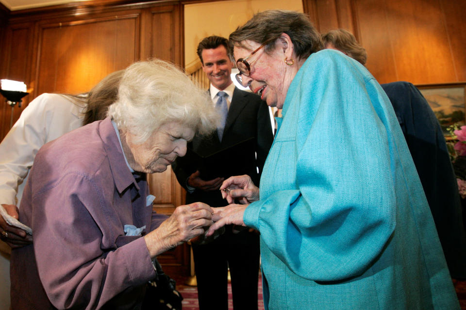 FILE - In this June 16, 2008, file photo, Del Martin, left, places a ring on her partner Phyllis Lyon, right, during their wedding ceremony officiated by then-San Francisco Mayor Gavin Newsom, center, at City Hall in San Francisco. The hilltop cottage of the couple that became the first same-sex partners to legally marry in San Francisco has become a city landmark. The San Francisco Board of Supervisors voted unanimously Tuesday, May 4, 2021, to give the 651 Duncan St. home of the lesbian activists landmark status. The home in the Noe Valley neighborhood is expected to become the first lesbian landmark in the western United States, the San Francisco Chronicle reported. (AP Photo/Marcio Jose Sanchez, File)