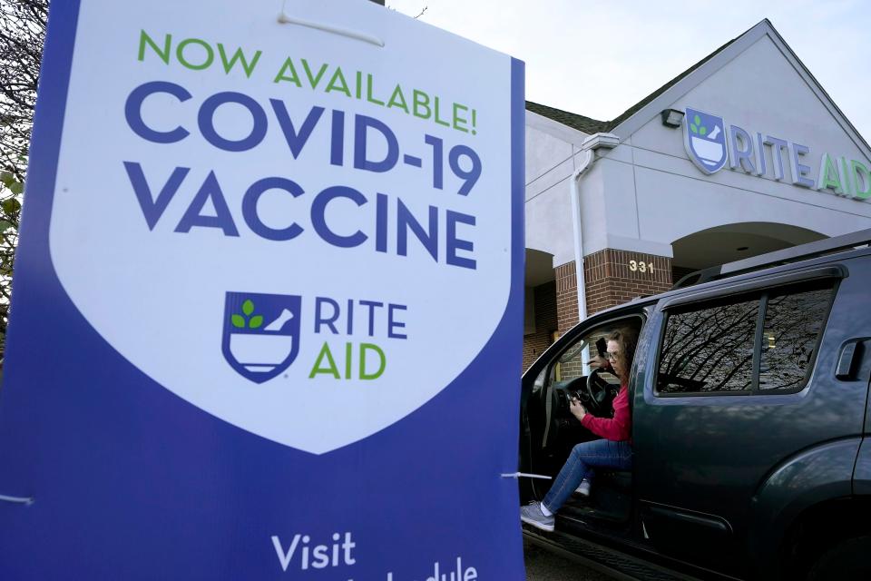 A woman is parked near a COVID-19 vaccine sign as she arrives at a Rite Aid pharmacy in Nashua, New Hampshire.