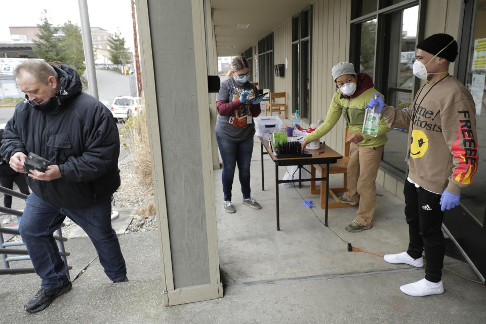 In this March 27, 2020 photo, Garrett McIntyre, left, arrives to pick up medication for opioid addiction at a clinic in Olympia, Wash., that is currently meeting patients outdoors and offering longer prescriptions in hopes of reducing the number of visits and the risk of infection due to the outbreak of the new coronavirus. The coronavirus pandemic is challenging the millions who struggle with drug and alcohol addiction and threatening America's progress against the opioid crisis, said Dr. Caleb Alexander of Johns Hopkins' school of public health. (AP Photo/Ted S. Warren)