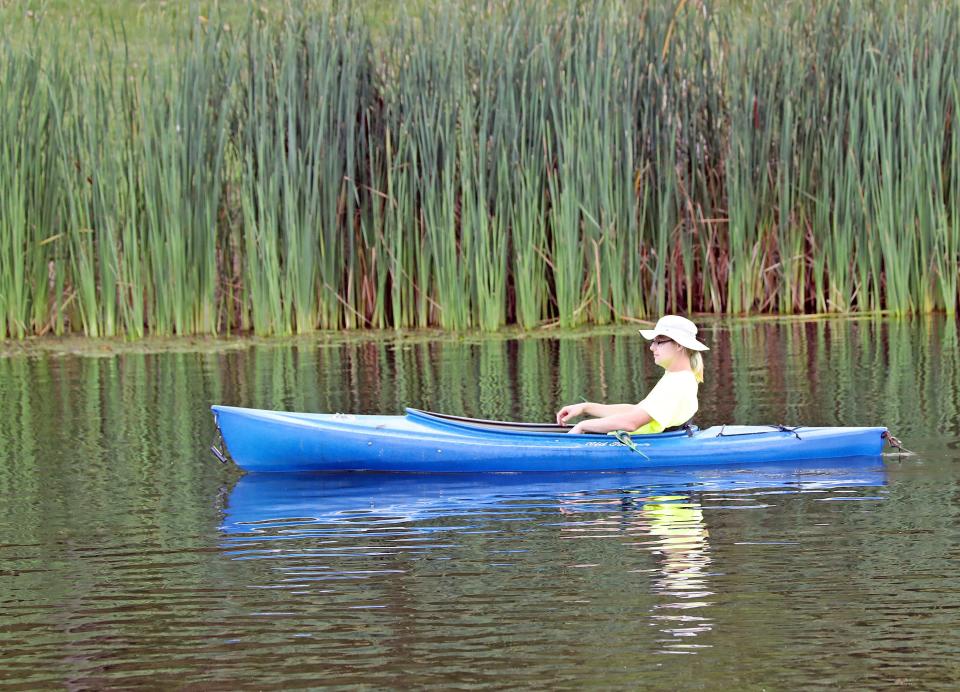 A kayaker floats along in Discovery Pond during the annual “Glow Wild” at the Jester Park Nature Center in Granger featuring a giant bonfire, live birds of prey, horse-drawn wagon rides, canoeing, nature hikes, S’mores, insect zoo, three musical acts, and much more.