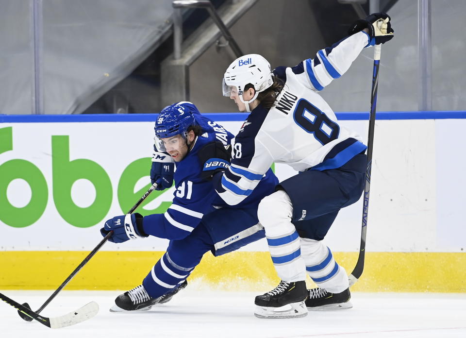 Toronto Maple Leafs center John Tavares (91) tries to drive past Winnipeg Jets defenseman Sami Niku (8) during the third period of an NHL hockey game in Toronto on Monday, Jan. 18, 2021. (Nathan Denette/The Canadian Press via AP)