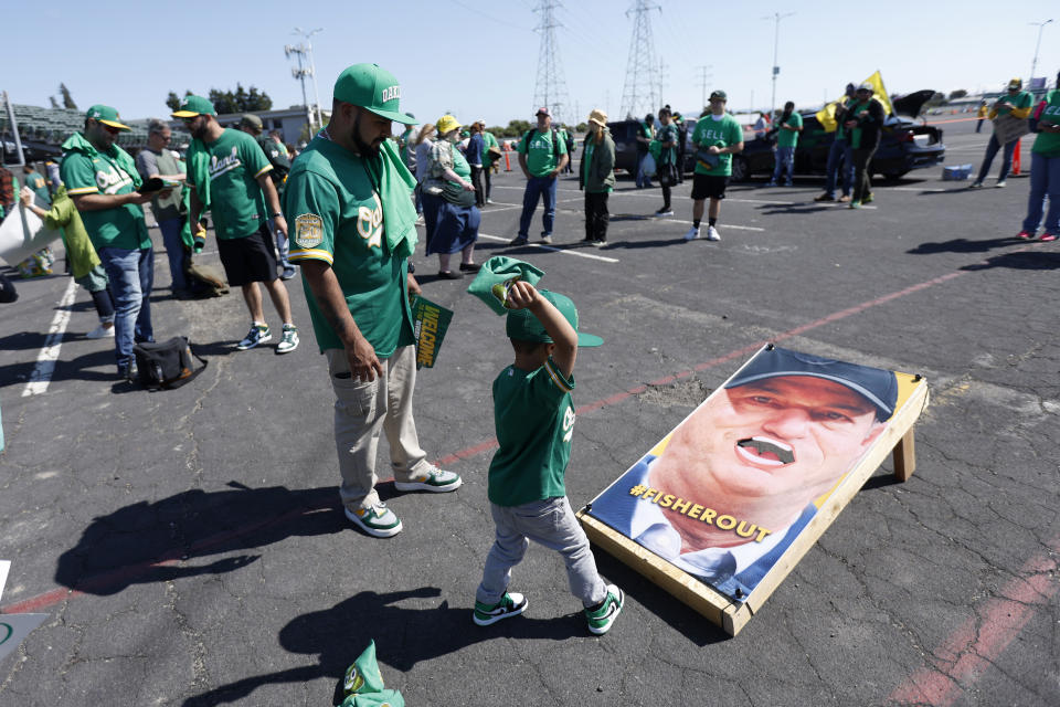 Pepito Mendez, center, plays cornhole with his father, Paco Mendez, of Pittsburg, Calif., outside Oakland Coliseum to protest the Oakland Athletics' planned move to Las Vegas, before a baseball game between the Athletics and the Tampa Bay Rays in Oakland, Calif., Tuesday, June 13, 2023. (AP Photo/Jed Jacobsohn)