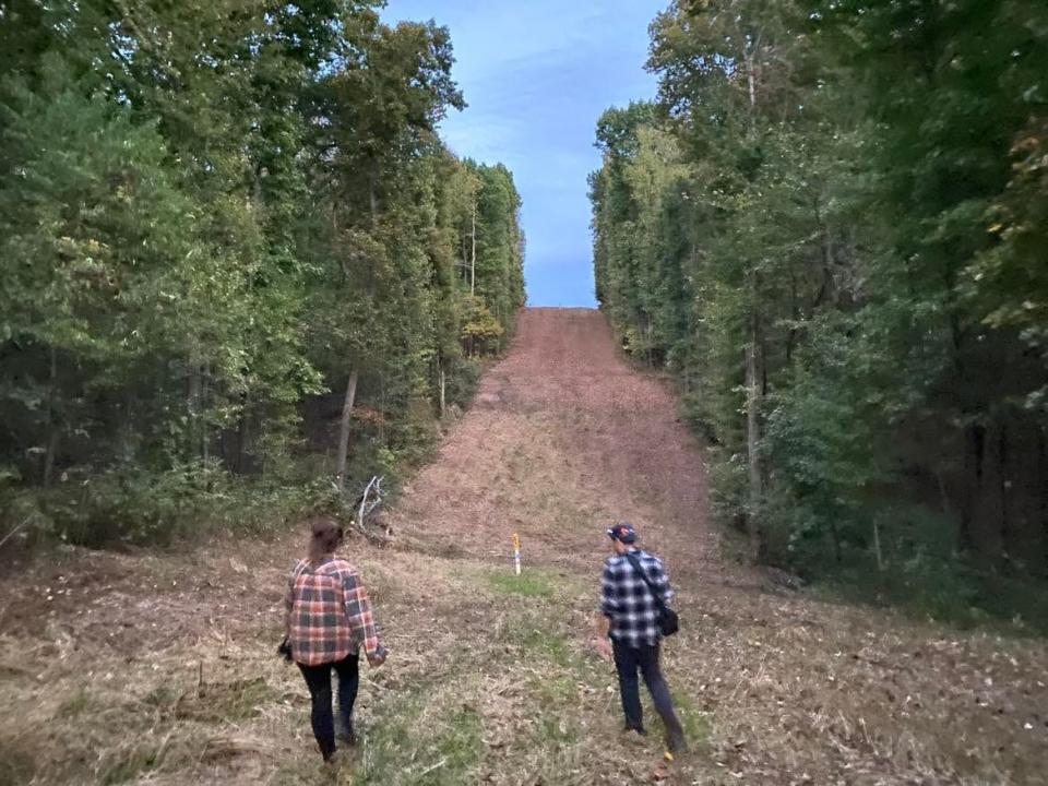 Heather Moser, left, and Seth Breedlove walk toward an incline and clearing in a wooded and rural area outside Minerva in Carroll County. Breedlove, a filmmaker who has released documentaries and movies about Bigfoot and strange occurrences, said he spotted what he believes was a bipedal creature in the area in September.