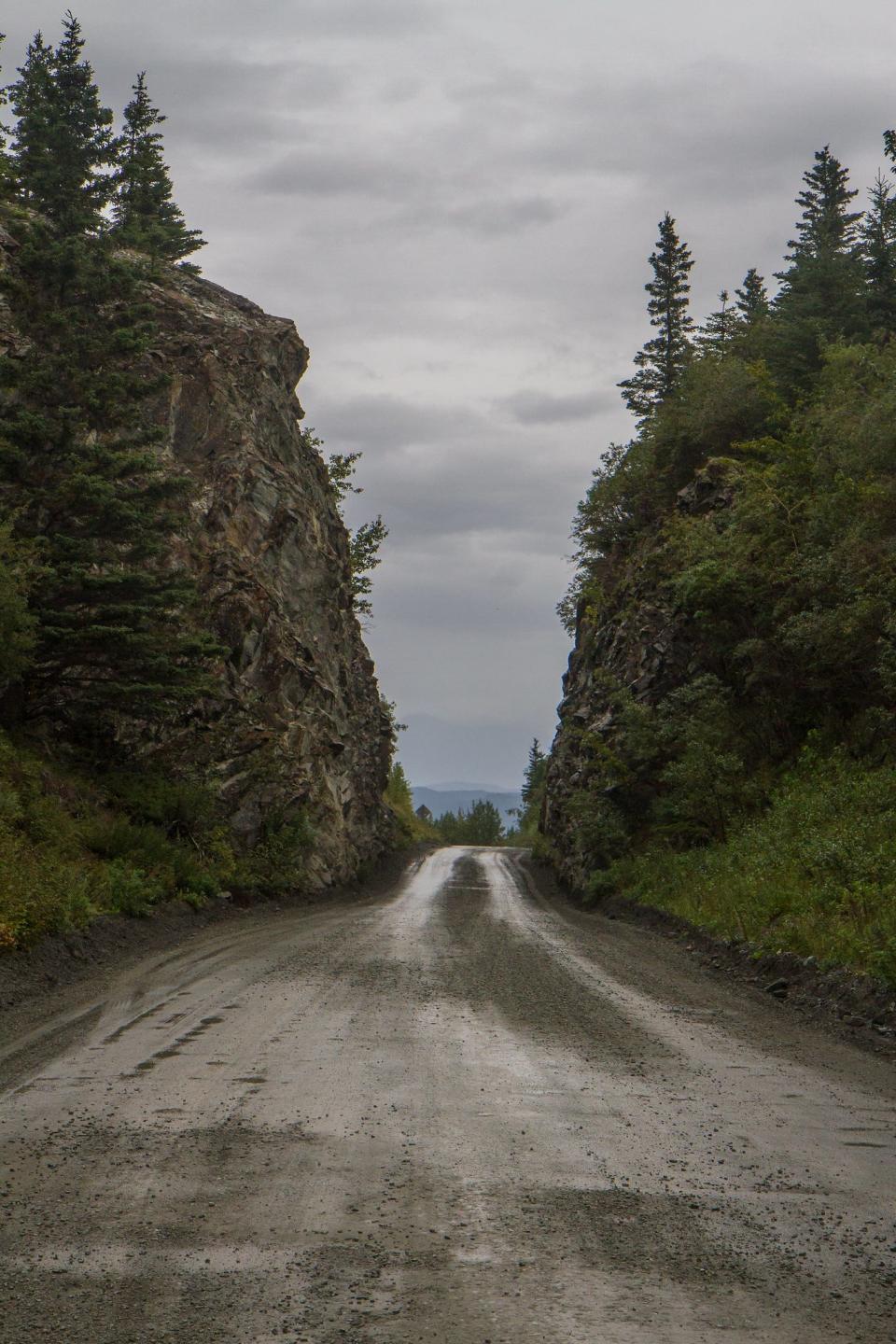 A road with boulders and trees on either side.