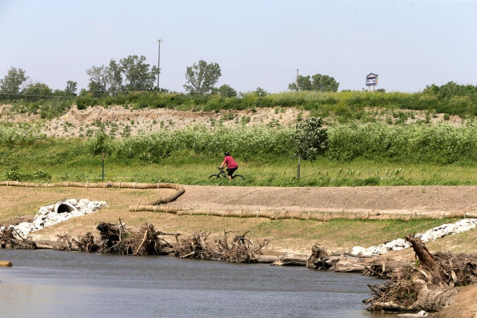 A cyclist bikes past a portion of Clear Creek that is being restored Thursday, June 6, 2024 in Coralville, Iowa.