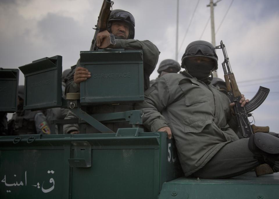 Afghan police men ride on top of their armored vehicle as they rush to the scene as Taliban militants attacked the main Afghan election commission's headquarters in the outskirts of Kabul, Afghanistan, firing on the compound with rocket-propelled grenades and heavy machine guns from a house outside its perimeter wall, Saturday, March 29, 2014. Dozens of employees and other people who had been inside the Independent Election Commission compound took cover in the basement, and no casualties were reported. But two warehouses were hit and set on fire, witnesses said. (AP Photo/Anja Niedringhaus)