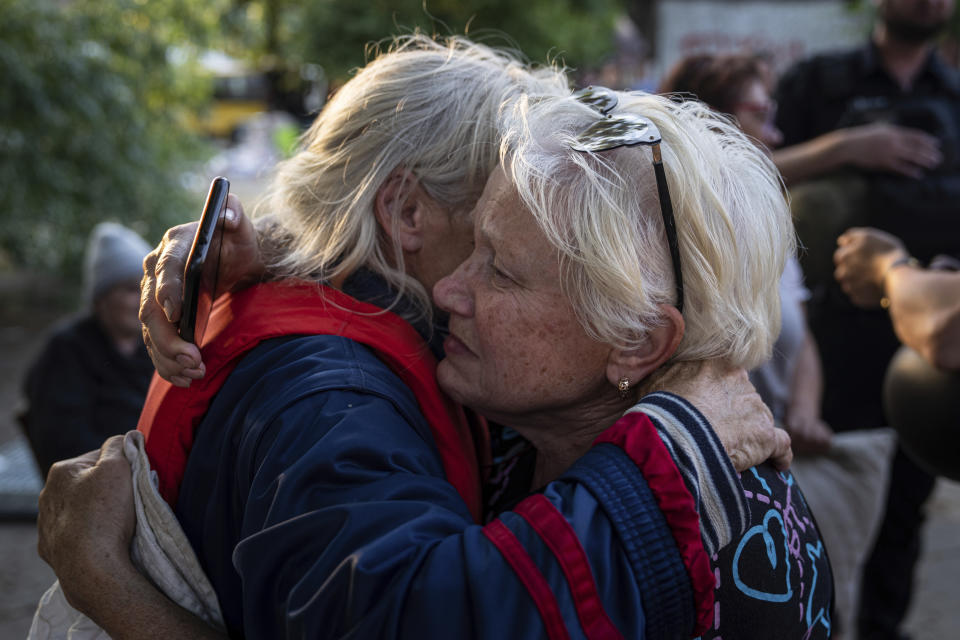 Tetyana (derecha) abraza a su vecina Hanna tras ser evacuadas desde la anegada localidad de Kardashynka, en la orilla este del río Dniéper, ocupada por Rusia, a Jersón, Ucrania, en la margen contraria, el 9 de junio de 2023. En los primeros días tras la rotura de la represa, los rescatistas ucranianos, sorteando a los drones y el peligro de los francotiradores rusos, cruzaron el río Dniéper para evacuar a los civiles de zonas afectadas por las inundaciones en la orilla ocupada por Rusia. (AP Foto/Evgeniy Maloletka)