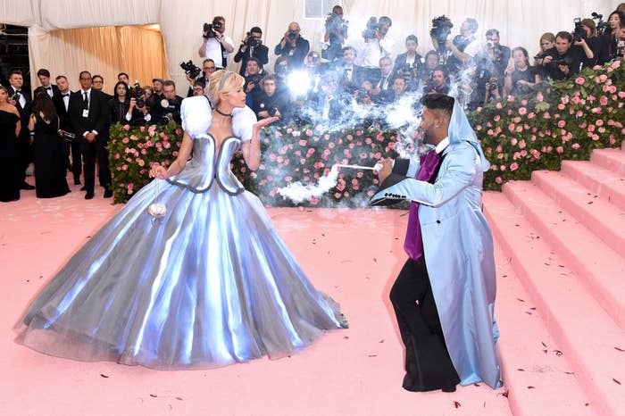 Law Roach waving a wand at Zendaya to illuminate her dress on the red carpet
