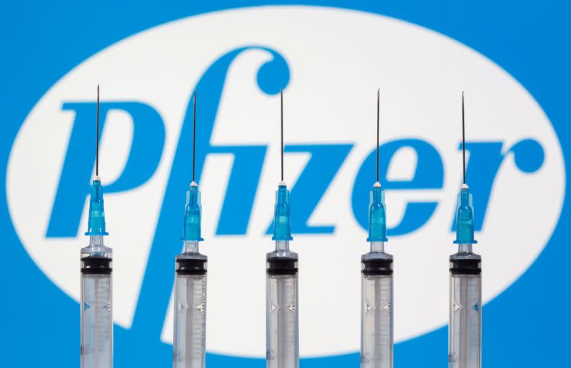 FILE PHOTO: Syringes are seen in front of a displayed Pfizer logo in this illustration