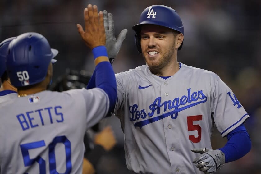 Los Angeles Dodgers' Freddie Freeman (5) high fives Mookie Betts (50) after hitting a three-run home run against the Arizona Diamondbacks during the second inning of a baseball game, Thursday, May 26, 2022, in Phoenix. (AP Photo/Matt York)