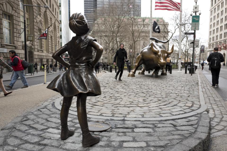 A statue titled "Fearless Girl" faces the Wall Street bull, Wednesday, March 8, 2017, in New York. A big investment firm, State Street Global Advisors, put the statue there to highlight International Women's Day. The work by artist Kristen Visbal. (AP Photo/Mark Lennihan)