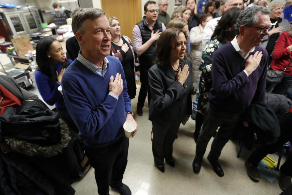 Former Colorado Gov. John Hickenlooper, left, stands with Democratic presidential candidate Sen. Kamala Harris, right, during the Pledge of Allegiance at the Story County Democrats' annual soup supper fundraiser, Saturday, Feb. 23, 2019, in Ames, Iowa. (AP Photo/Charlie Neibergall)
