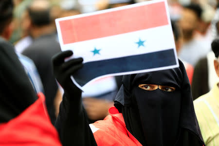 A woman supporter of Iraqi Shi'ite cleric Moqtada al-Sadr holds a Syrian flag during a protest against western air strikes on Syria, at Tahrir Square in Baghdad, Iraq April 15, 2018. REUTERS/Thaier Al-Sudani