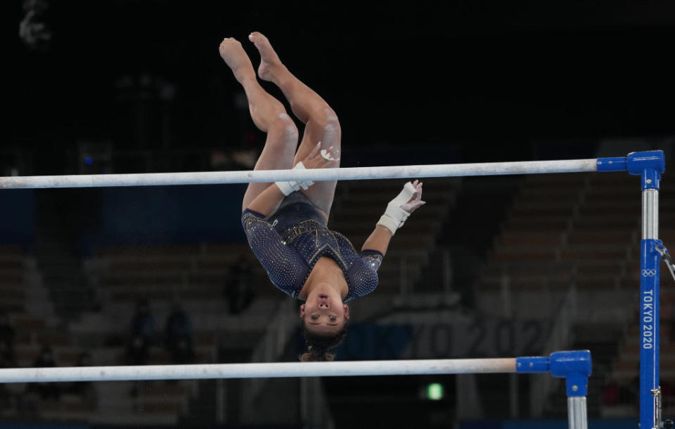 Suni Lee focused on the bar as she's upside down in mid-air