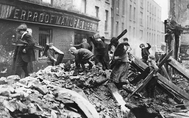 Children collect firewood from the ruined buildings damaged in the Easter Rising   - Credit: Getty Images