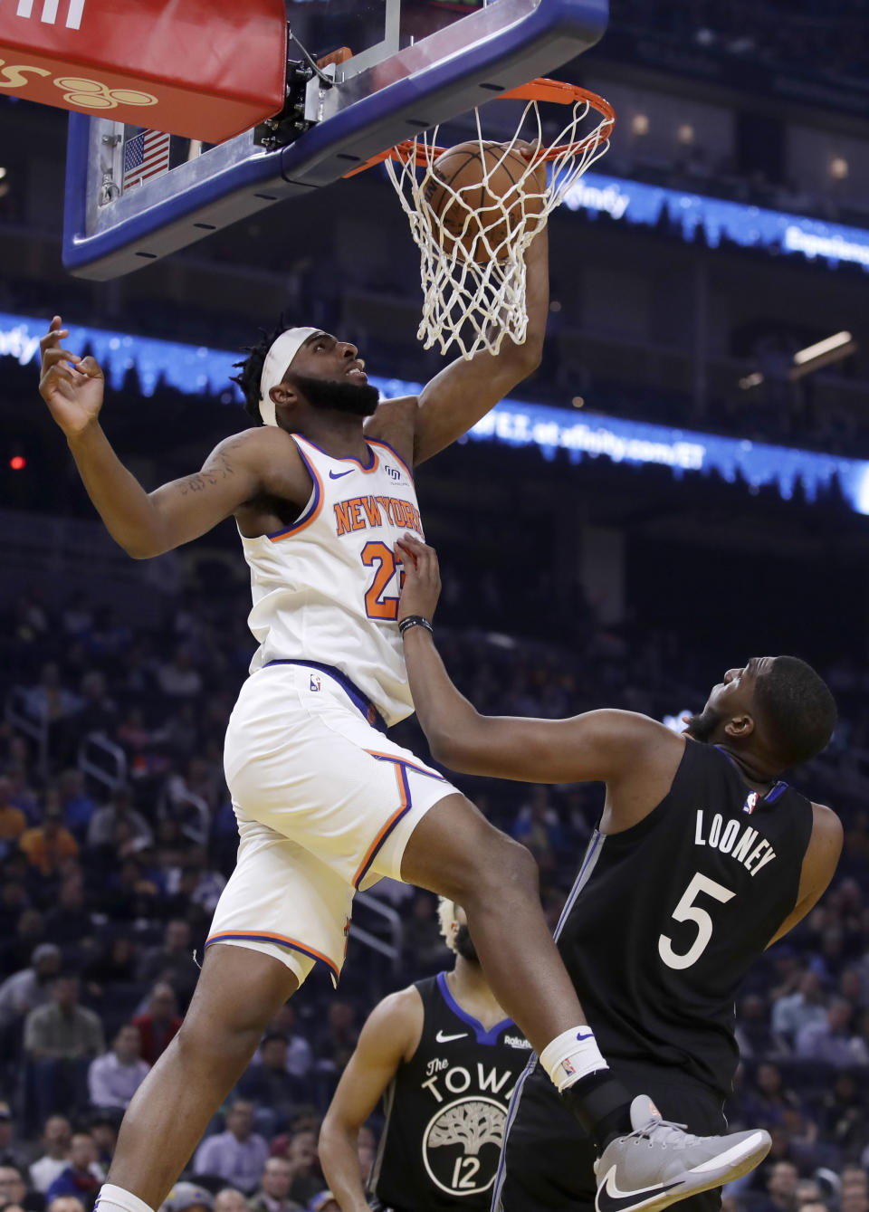 New York Knicks' Mitchell Robinson, left, scores over Golden State Warriors' Kevon Looney (5) in the first half of an NBA basketball game, Wednesday, Dec. 11, 2019, in San Francisco. (AP Photo/Ben Margot)