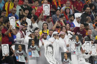 Spectators hold photos of Forman German international Mesut Ozil on the stands and cover their mouths during the World Cup group E soccer match between Spain and Germany, at the Al Bayt Stadium in Al Khor , Qatar, Sunday, Nov. 27, 2022. (AP Photo/Matthias Schrader)