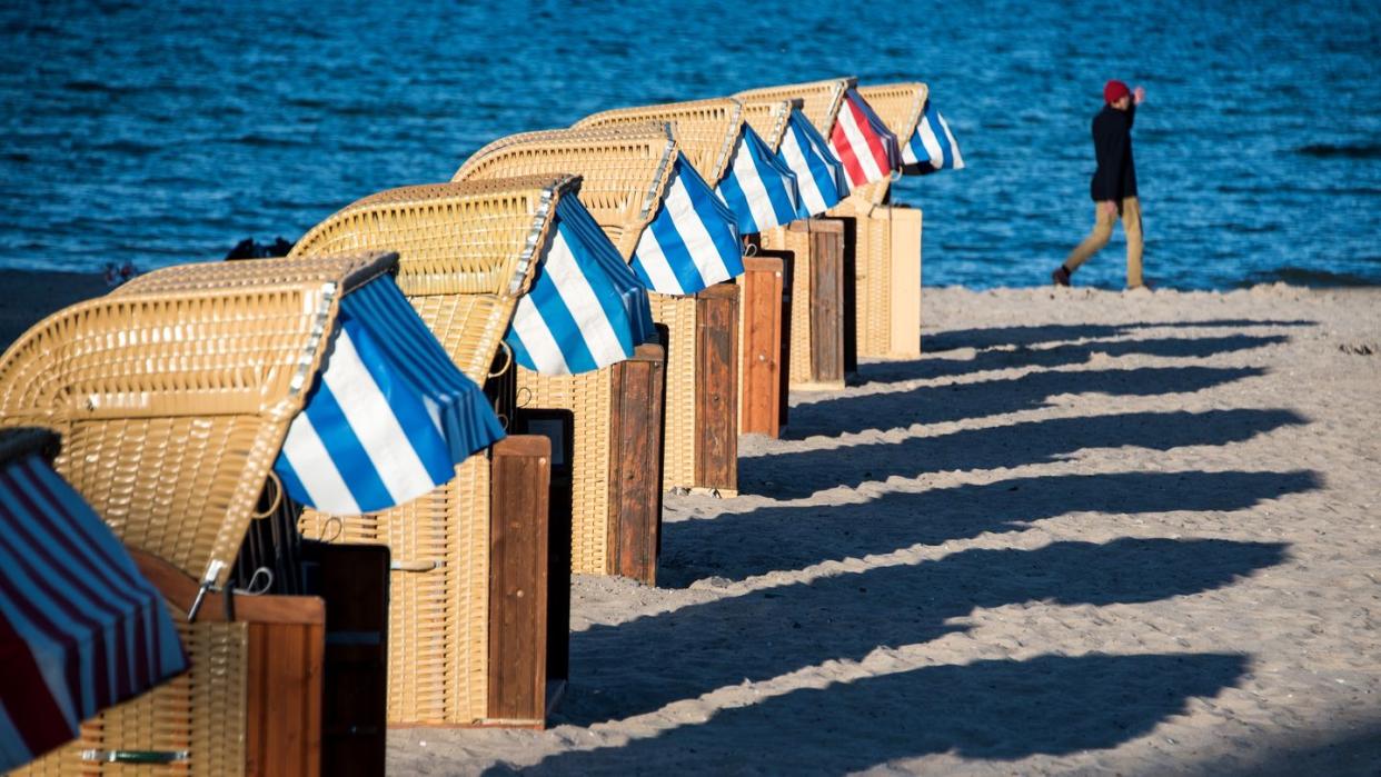 Strandkörbe werfen am Abend lange Schatten auf den Strand an der Ostsee bei Lübeck-Travemünde.