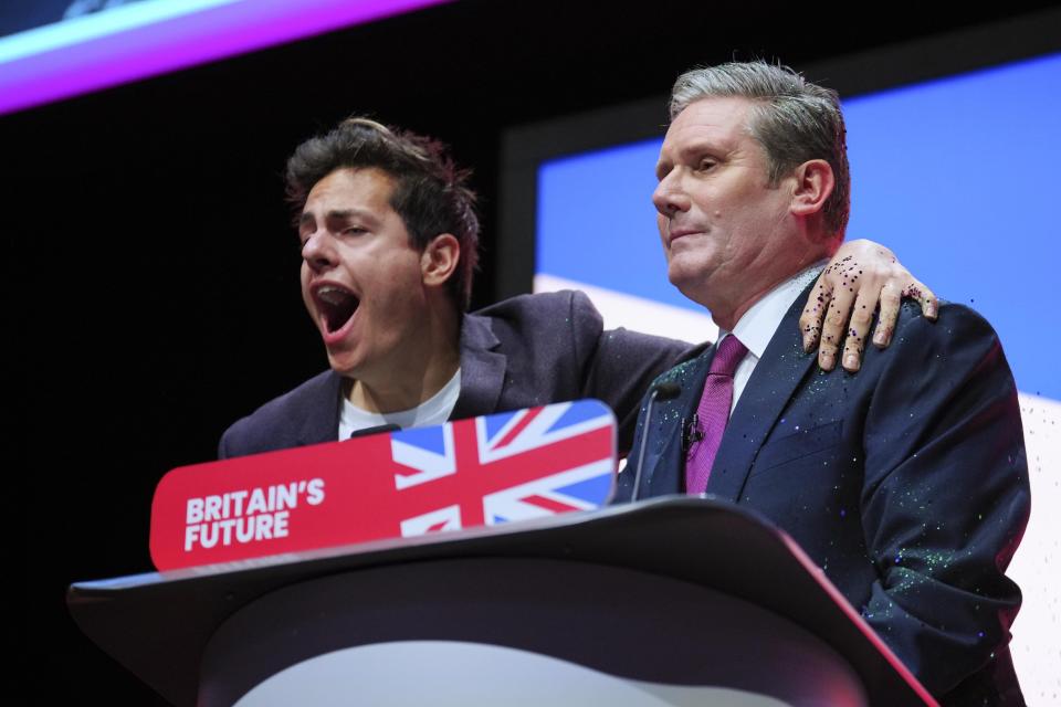 An unidentified man hugs Britain's opposition Labour Party leader Keir Starmer during his speech at the Labour Party conference in Liverpool, England, Tuesday, Oct. 10, 2023.(AP Photo/Jon Super)