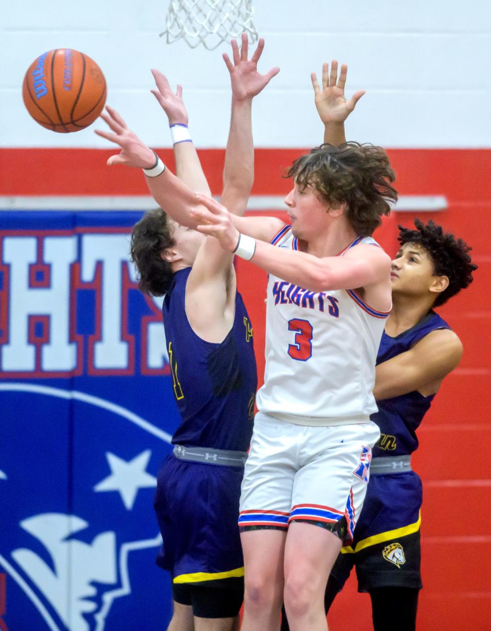 Peoria Heights' Camron Williams (3) passes around Peoria Christian defender in the first half of their high school basketball game Friday, Jan. 26, 2024 at Peoria Heights High School. The Chargers defeated the Patriots 60-58.