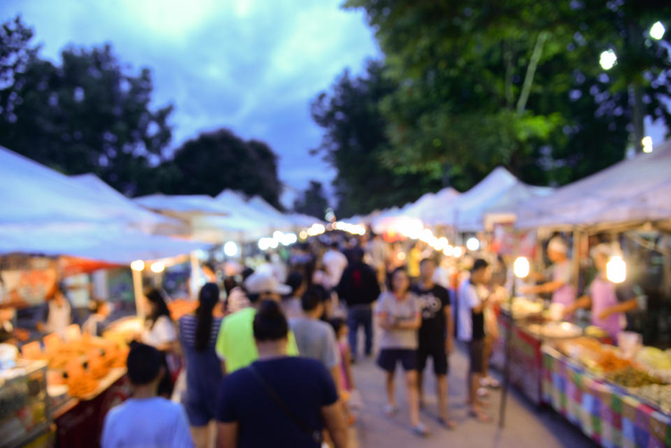 A community fair with a bunch of tented booths and people walking through them