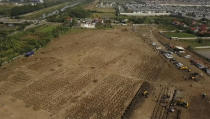 In this image from drone video, backhoes dig additional burial plots at the Rorotan cemetery, a graveyard built for COVID-19 victims in Jakarta, Indonesia on July 23, 2021. Indonesia surpassed the grim milestone of 100,000 official COVID-19 deaths on Wednesday, Aug. 4, 2021, as the country struggles with its worst pandemic year fueled by the delta variant, with growing concerns that the actual figure could be much higher with people also dying at home. (AP Photo/Andi Jatmiko)