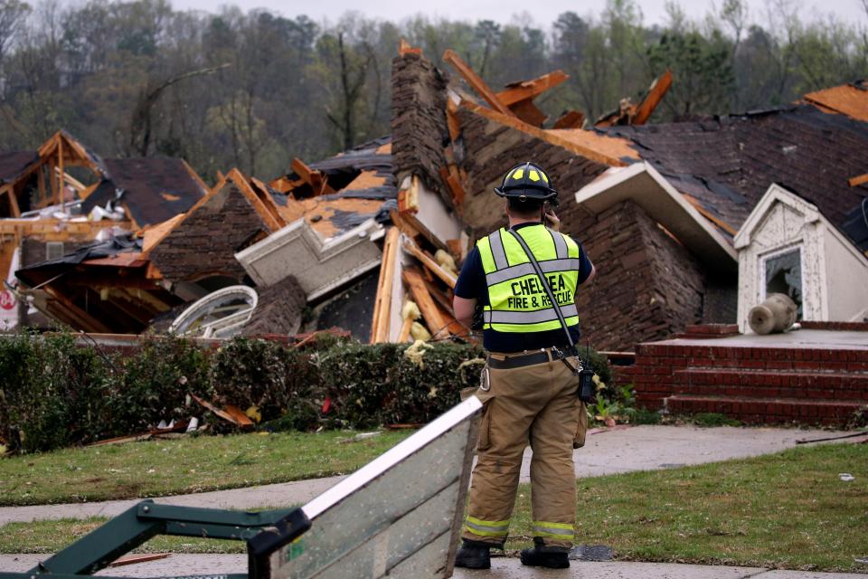 A firefighter is pictured surveying damage to a house after an apparent tornado touched down near Birmingham, Alabama, on Thursday. Authorities reported major tornado damage south of Birmingham as strong storms moved through the state.