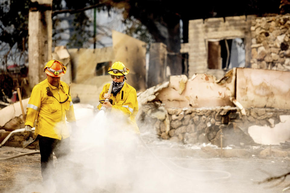 A Los Angeles County firefighter extinguishes hot spots at a scorched residence while battling the Lake Fire in the Angeles National Forest, Calif., north of Santa Clarita on Thursday, Aug. 13, 2020. Light winds and scattered thundershowers early Thursday helped calm the flames of a huge wildfire that prompted evacuations north of Los Angeles, and firefighters hoped to rein in the blaze before temperatures spike later in the day. (AP Photo/Noah Berger)