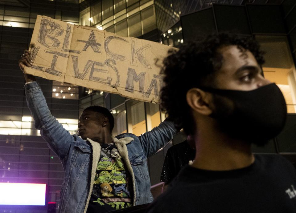 A protester holds up a sign during a night of clashes in downtown Detroit.