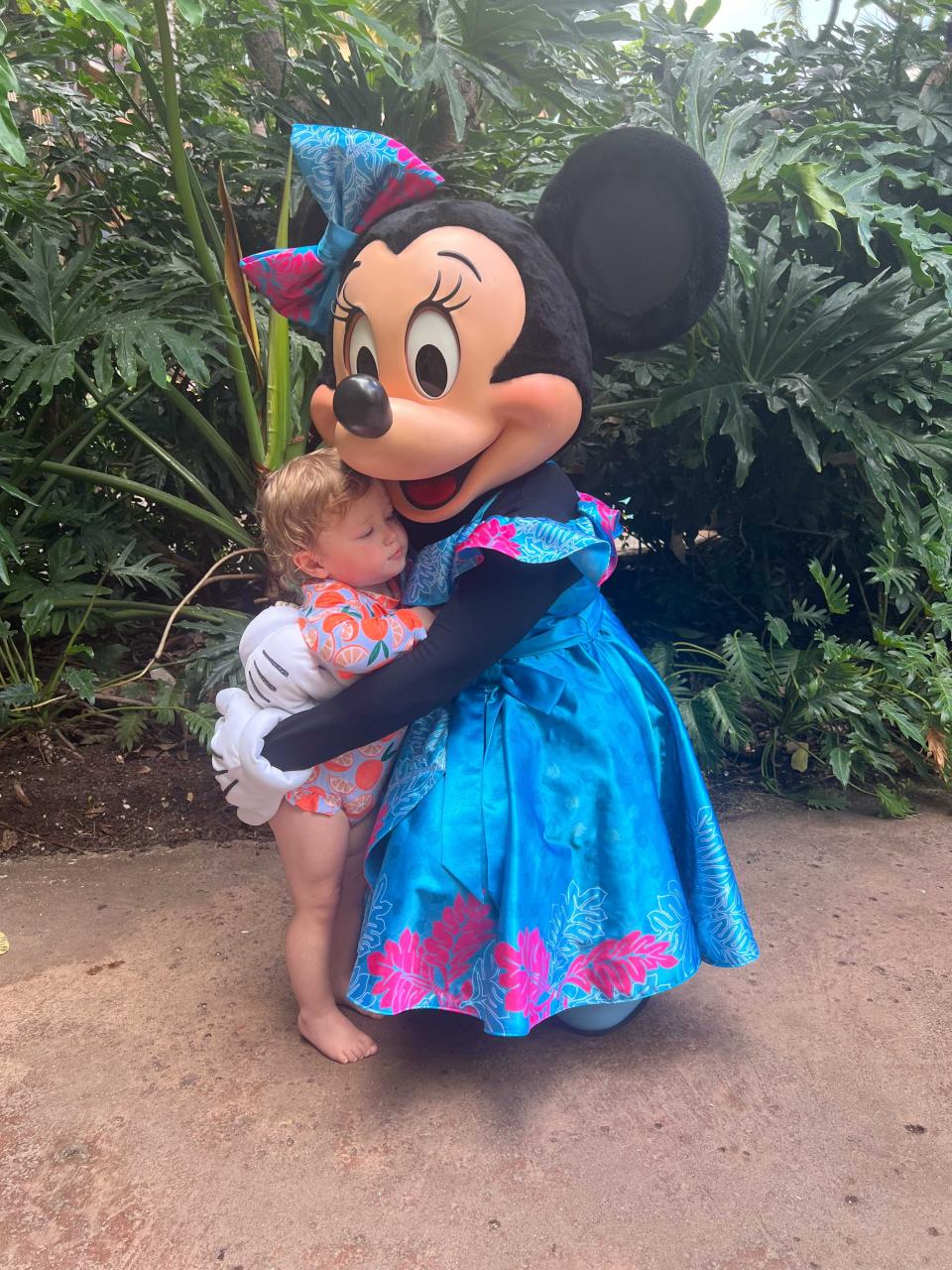 A young girl being embraced by Minnie Mouse