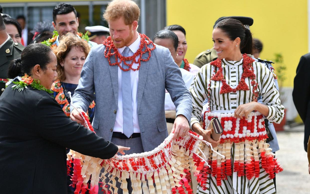 The Duke and Duchess of Sussex are given ta'ovala, a traditional Tongan dress wrapped around the waist, as they visit an exhibition of handicrafts, mats and tapa cloths at the Fa'onelua Convention Centre on the second day of the royal couple's visit to Tonga in 2018 - Dominic Lipinski/PA Wire