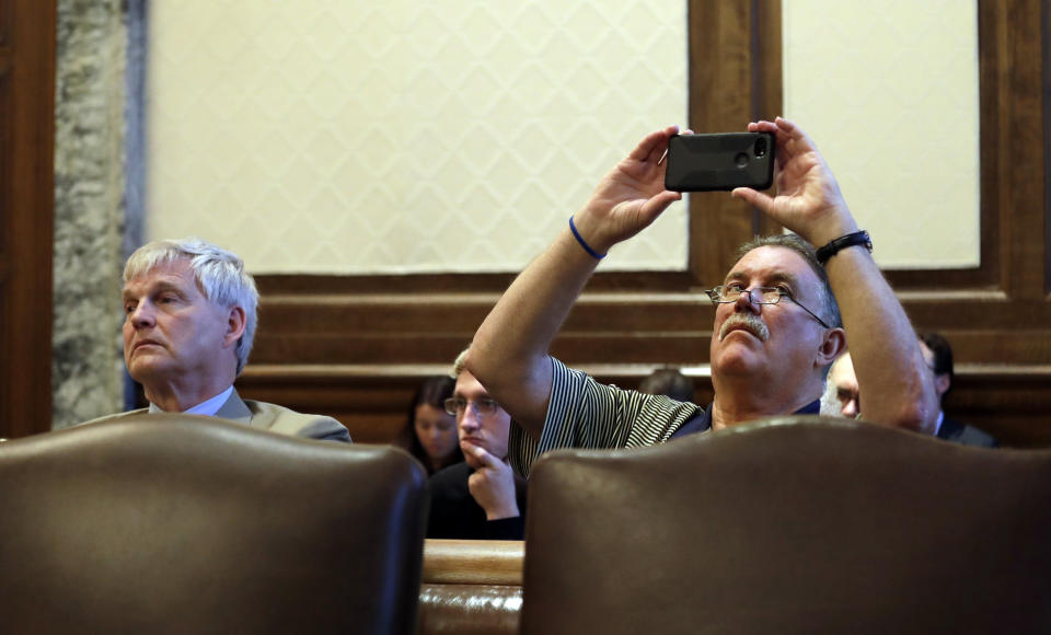 David Zeeck, right, retired publisher of The (Tacoma) News Tribune, takes a photo of proceedings as he sits with Rowland Thompson, executive director of Allied Daily Newspapers of Washington, during a hearing before the Washington Supreme Court Tuesday, June 11, 2019, in Olympia, Wash. The court heard oral arguments in the case that will determine whether state lawmakers are subject to the same disclosure rules that apply to other elected officials under the voter-approved Public Records Act. The hearing before the high court was an appeal of a case that was sparked by a September 2017 lawsuit filed by a media coalition, led by The Associated Press. (AP Photo/Elaine Thompson)