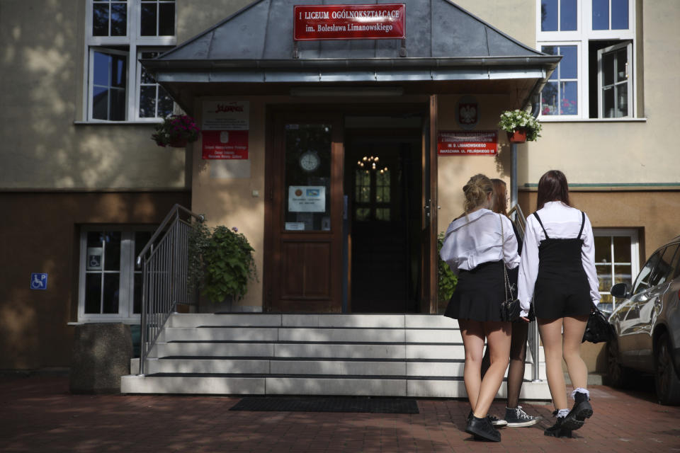 Students stand in front of the entrance to the Limanowski High School in Warsaw, Poland, Thursday, Sept. 1, 2022. The public schools in Poland are facing a shortage of teachers, a problem that is growing increasingly serious each year as people leave the profession over low wages and policies of a government which they fear does not value them. A teachers union and teachers say the situation threatens the education of the country's youth, though the government insists that they are exaggerating the scale of the problem. (AP Photo/Michal Dyjuk)