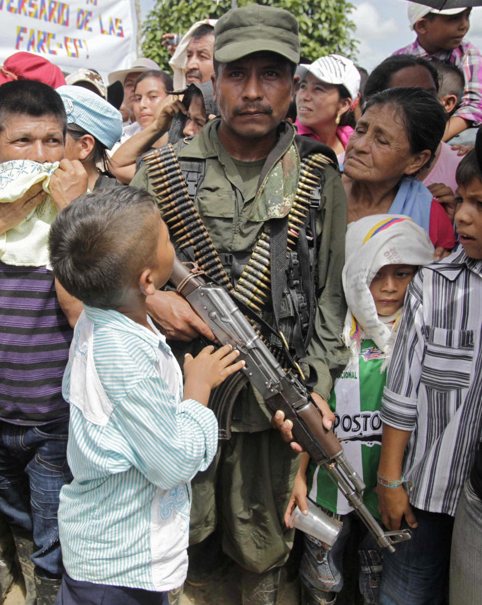 A child looks up at a member of the Revolutionary Armed Forces of Colombia (FARC) during a ceremony for the rebel handover of a French journalist in San Isidro in southern Colombia, Wednesday, May 30, 2012. French journalist Romeo Langlois, who was taken by rebels of the Revolutionary Armed Forces of Colombia (FARC) on April 28 when they attacked troops he was accompanying on a cocaine-lab eradication mission, was handed over by the rebels to a delegation in San Isidro on Wednesday. (AP Photo/Fernando Vergara)