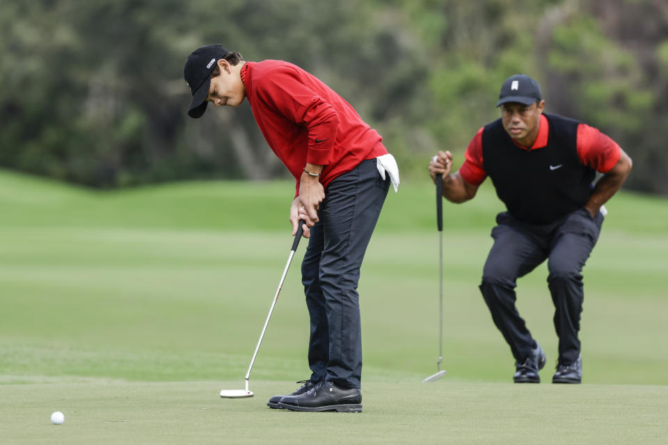 Charlie Woods, left, putts on the 2nd green while Tiger Woods, right, watches during the final round of the PNC Championship golf tournament Sunday, Dec. 18, 2022, in Orlando, Fla. (AP Photo/Kevin Kolczynski)