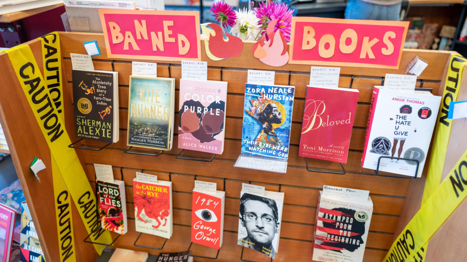 A store display of several books decorated with caution tape and a sign reading: Banned Books.