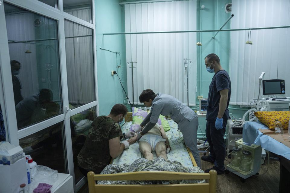 Medics treat en elderly woman at the ICU department in the hospital of Zolochiv, Kharkiv region, Ukraine, Sunday, July 31, 2022. Ukraine's health care system already was struggling due to corruption, mismanagement and the COVID-19 pandemic. But the war with Russia has only made things worse, with facilities damaged or destroyed, medical staff relocating to safer places and many drugs unavailable or in short supply. (AP Photo/Evgeniy Maloletka)