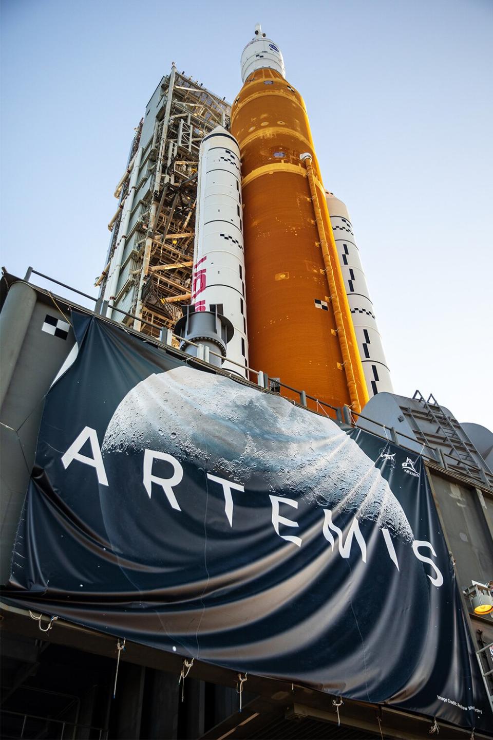 In this view looking up, NASA’s crawler-transporter 2 – adorned with an Artemis banner – can be seen bearing the weight of the agency’s Artemis I Moon rocket and mobile launcher as it carries the duo to Kennedy Space Center’s Launch Complex 39B in Florida on June 6, 2022. The rocket rolled out of the Vehicle Assembly Building in the early morning hours to travel the 4.2 miles to the launch pad for NASA’s next wet dress rehearsal attempt ahead of the Artemis I launch. The first in an increasingly complex series of missions, Artemis I will test the Space Launch System rocket and Orion spacecraft as an integrated system prior to crewed flights to the Moon. Through Artemis, NASA will land the first woman and first person of color on the lunar surface, paving the way for a long-term lunar presence and using the Moon as a steppingstone before venturing to Mars.