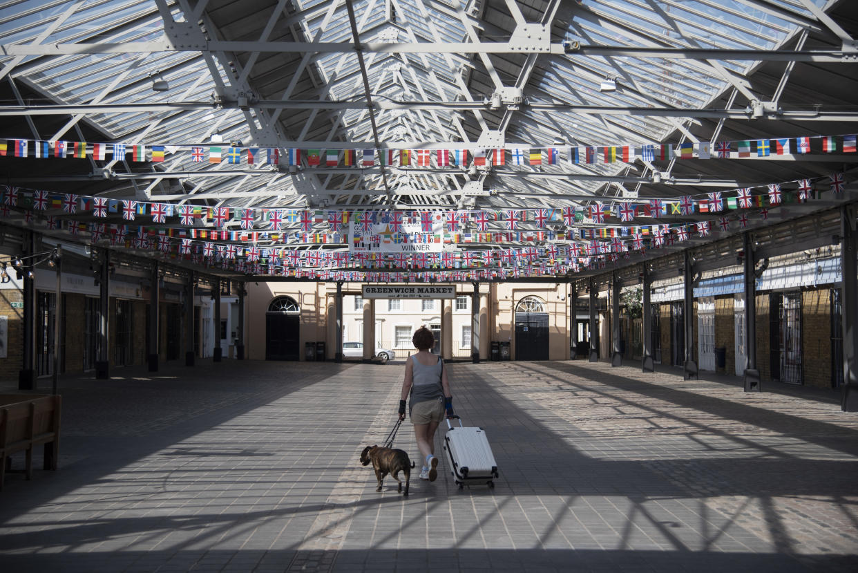 A women walks through an empty Greenwich Market with a dog and suitcase on 15th April 2020 in Greenwich, London, United Kingdom. Chancellor of the Exchequer, Rishi Sunak has said the Office for Budget Responsibility (OBR), the UK's tax and spending watchdog suggests the coronavirus crisis will have "serious implications" for the UK economy, warning the pandemic could see the economy shrink by a record 35% by June, increasing unemployment by over 2 million and sending the budget deficit to its highest since World War II. (photo by Claire Doherty/In Pictures via Getty Images)