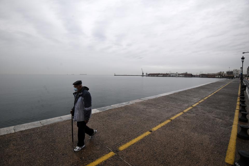 A pedestrian wearing a face mask against the spread of the coronavirus, walks on a coastal avenue during the lockdown to contain the spread of COVID-19 in the northern city of Thessaloniki, Greece, Tuesday, Nov. 3, 2020. Greece's government imposed a localized lockdown on its second largest city of Thessaloniki and the northern province of Serres, after major increases in the number of coronavirus infections there. (AP Photo/Giannis Papanikos)