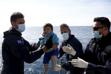 Greek Coast Guard officers move a baby from a dinghy carrying refugees and migrants aboard the Ayios Efstratios Coast Guard vessel, during a rescue operation at open sea between the Turkish coast and the Greek island of Lesbos, February 8, 2016. REUTERS/Giorgos Moutafis