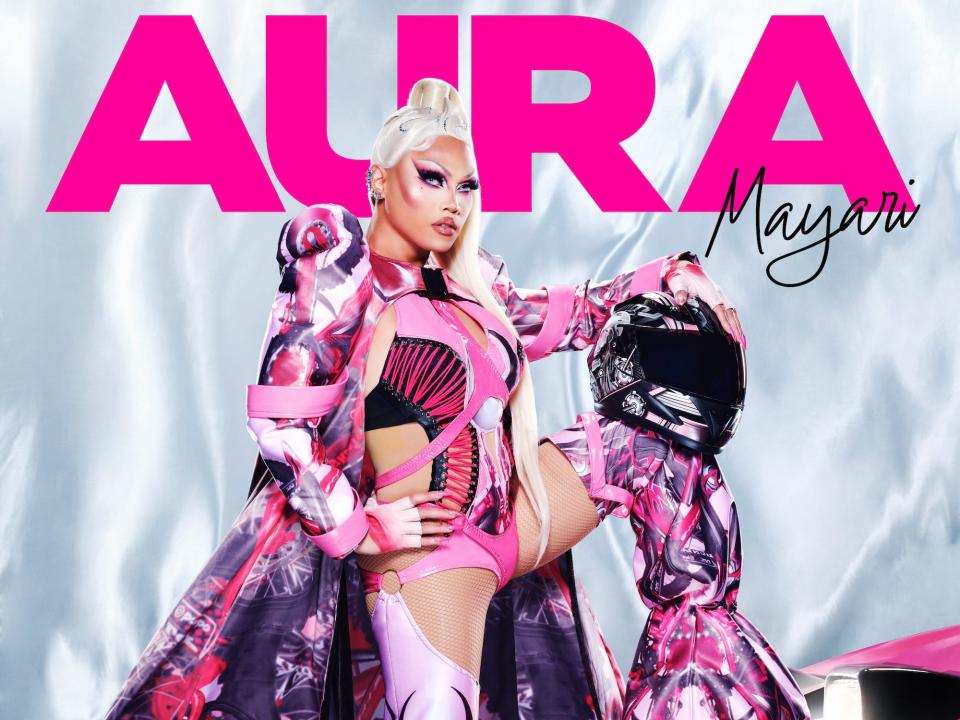 Aura Mayari poses for her "RuPaul's Drag Race" season 15 headshot in a pink, purple and red outfit and blonde hair.